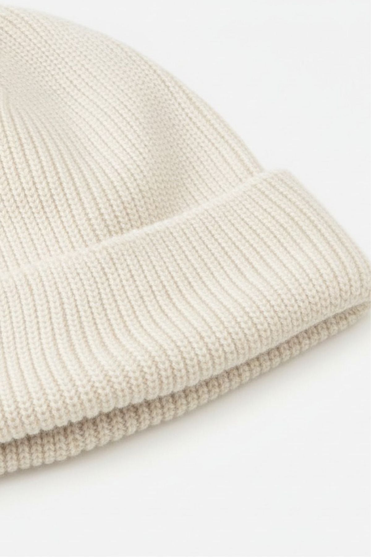 A close-up of the Rip Curl Oceanic Reg Beanie, a beige knit hat with a folded brim, displayed on a plain white background—ideal for keeping warm after water sports.