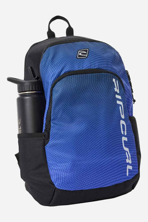 The Rip Curl Ozone 30L School Backpack in blue and black, crafted from recycled polyester, includes a side pocket perfectly sized for a water bottle. The front pocket is adorned with the iconic Rip Curl logo on its textured design, and it also features a top handle for easy carrying.