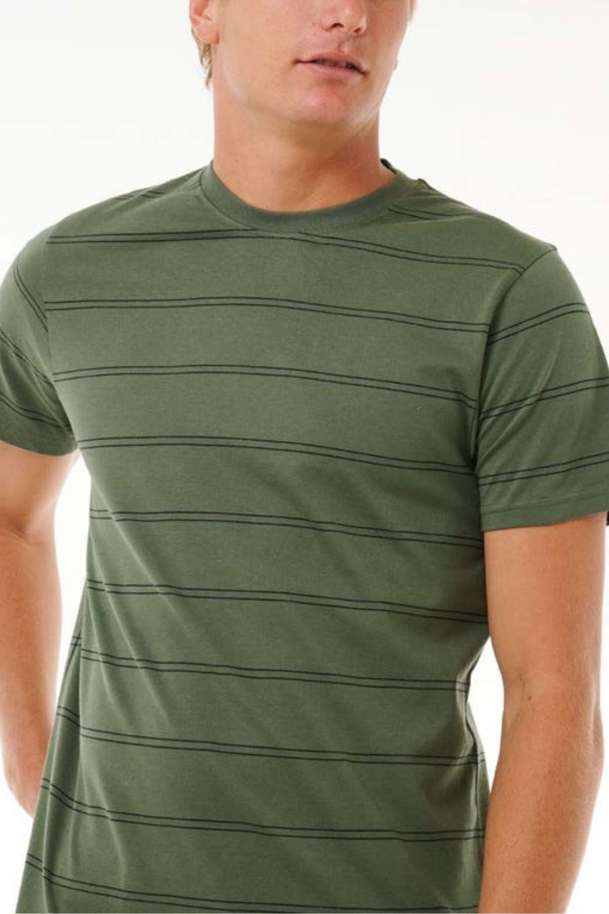 A person wearing a Rip Curl Plain Stripe Tee in green, featuring thin dark stripes and short sleeves, stands against a light background. The 100% cotton shirt has a distinctive look, with the individual's face partially out of frame.