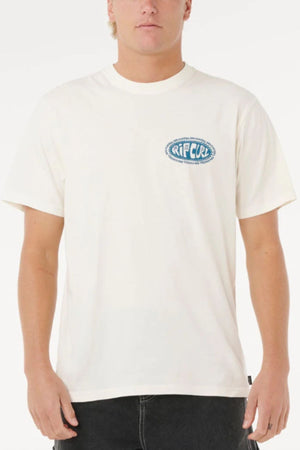 Someone wearing the Rip Curl Raw Energy De Oval Tee—a 100% cotton short-sleeve shirt featuring a blue and white "RIP CURL" logo on the left chest—is standing in front of a plain white background.