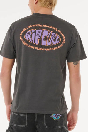 A person with short blond hair wears the Rip Curl Raw Energy De Oval Tee, a menβs cotton short-sleeve shirt with a large, colorful "Rip Curl" logo and "Raw Energy" text on the back. They face away from the camera in black shorts.