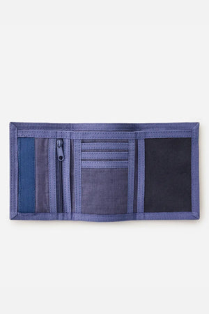 A purple Rip Curl Revival Cord Surf Wallet lies open, showing multiple card slots, a zippered pocket, and a mesh compartment.
