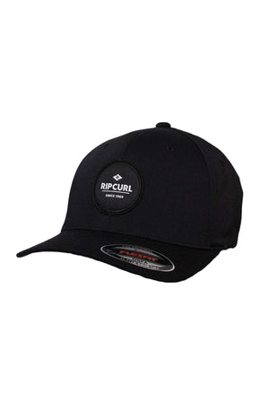 The Rip Curl Routine Flexfit Cap, in black, features a mid-profile design with a round "Rip Curl Since 1969" logo on the front and a curved brim with a product details sticker.