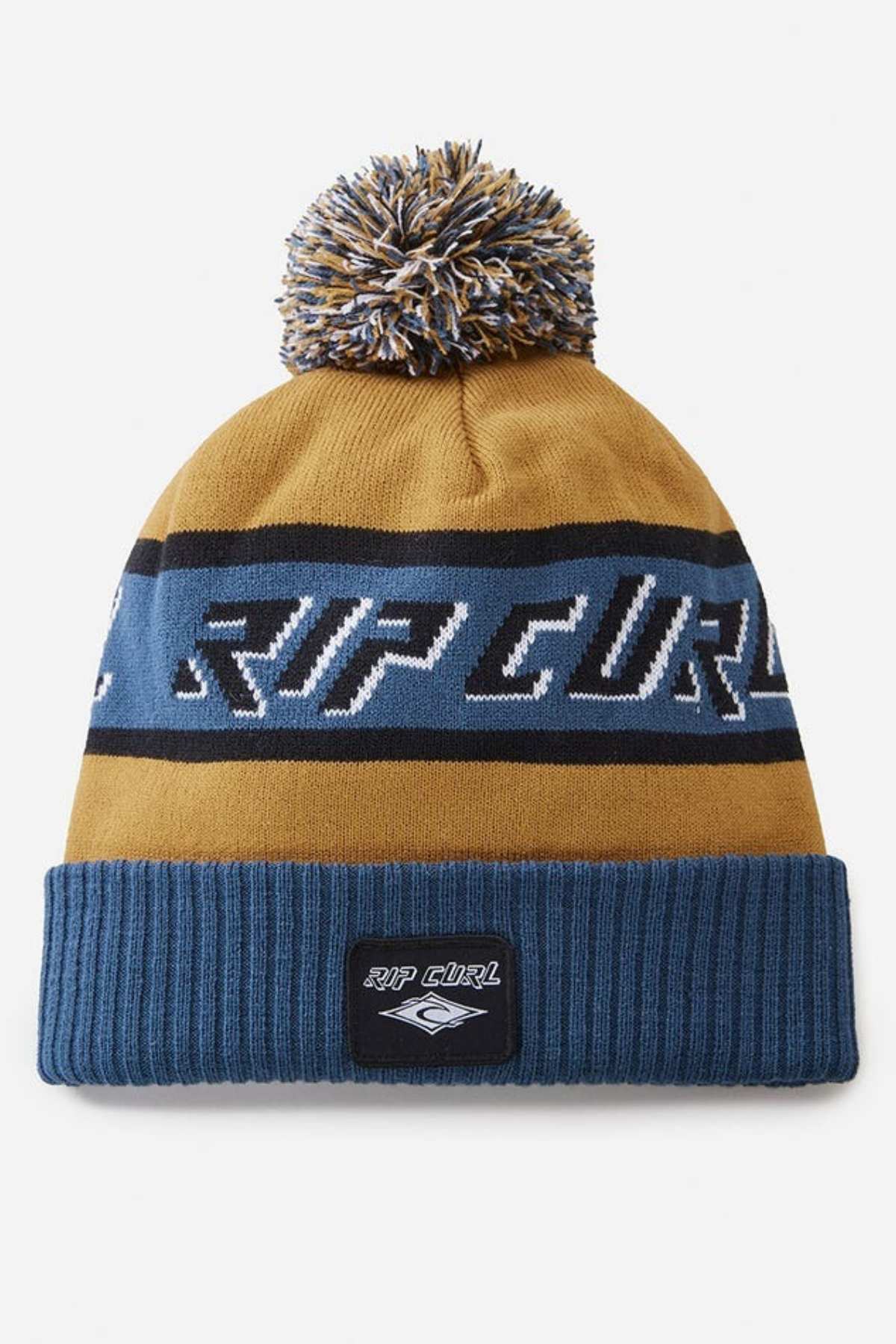 The Rip Curl Tow In Tall Beanie, made from soft acrylic yarn, features a pom-pom, mustard yellow and blue stripes, "Rip Curl" across the middle, a blue ribbed band, and a front patch with the brand logo.