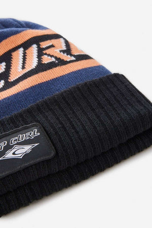 Close-up of the Rip Curl Tow In Tall Beanie featuring blue, orange, and black stripes, a soft acrylic yarn build, a black ribbed cuff, and a Rip Curl logo patch.