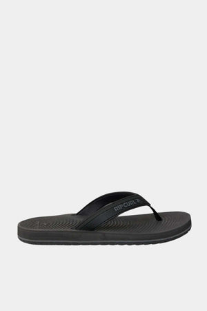 The Rip Curl Tunnels Bloom Thongs are black flip flops with a textured sole made from eco-friendly BLOOM algae foam and a simple strap featuring the "Rip Curl" logo, shown on a plain white background.
