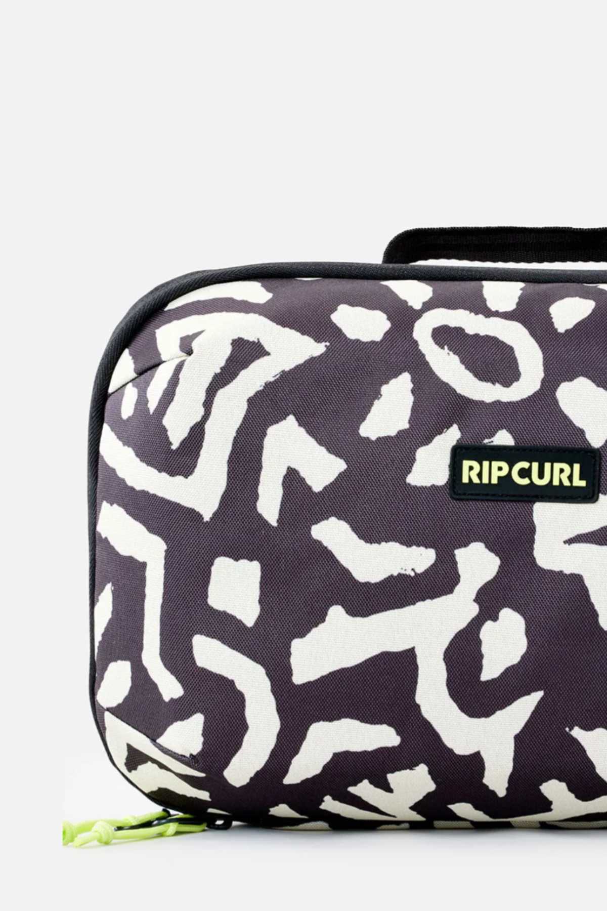 A detailed image showcases the Rip Curl Ultimate Beauty Case, adorned with a black and white abstract pattern. This travel toiletry bag features a nylon zipper, accented by a neon yellow zipper pull. The Rip Curl logo is prominently displayed on a black tag, making it an ideal travel companion for your beauty essentials.