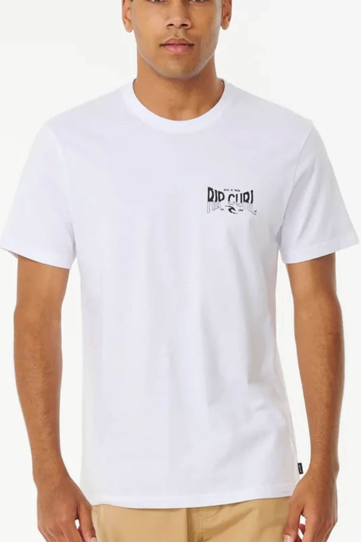 A person is wearing the Rip Curl Affinity Tee, a 100% cotton white shirt featuring a small left chest "Rip Curl" logo, paired with beige pants for a standard fit against a plain backdrop.