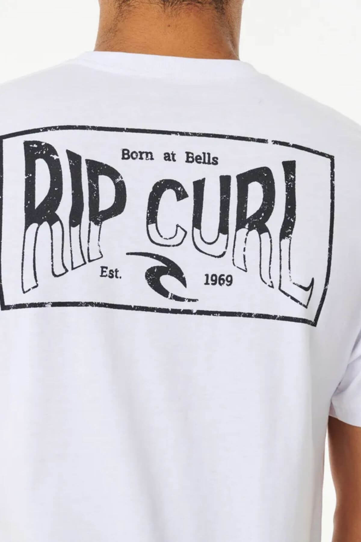 The image shows the Rip Curl Affinity Tee, a standard fit white t-shirt made of 100% cotton. It has a black rectangular graphic with "RIP CURL" in bold, "Born at Bells" above, and "Est. 1969" below a wave symbol on the back.