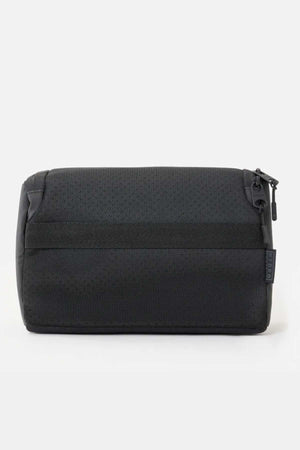 The Rip Curl F-Light Toiletry bag, with a textured fabric and zipper closure, is displayed on a white background. This black bag offers multiple compartments for organization, a ventilated mesh section, and a stylish side tag.