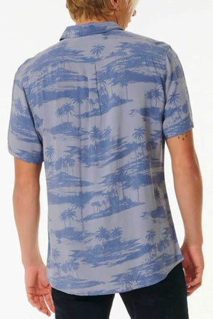 A person with short blond hair is seen from the back, wearing the Rip Curl Party Pack Short Sleeve Shirt with a tropical island and palm tree print, providing a comfortable fit against a plain white background.