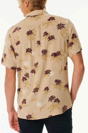 A man with blond hair, facing away from the camera, is wearing a Rip Curl Sun Razed Floral Short Sleeve Shirt featuring a brown and cream floral pattern against a plain white background.