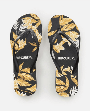 A pair of Rip Curl La Isla Bloom Thongs featuring black soles with a yellow and white floral pattern. The black straps are adorned with the discreetly printed Rip Curl logo. Crafted from BLOOM™ algae blended foam for a sustainable touch, the background remains plain white.