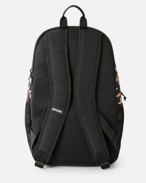 The Rip Curl Ozone 2.0 30L Backpack, made from recycled polyester, is shown from the back with padded shoulder straps, a top carrying handle, and mesh back panel. Subtle leafy side panels and "RIP CURL" on one strap complete the look.