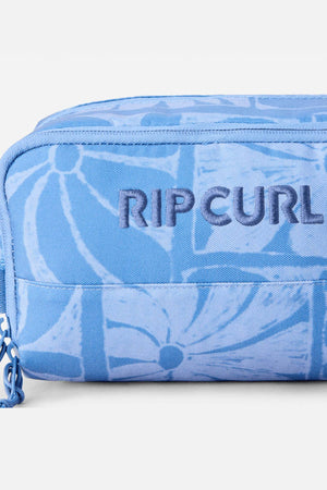 Close-up of the Rip Curl Mixed Toiletry Bag in light blue with a floral pattern and a dark blue embroidered "RIP CURL" logo on the front.