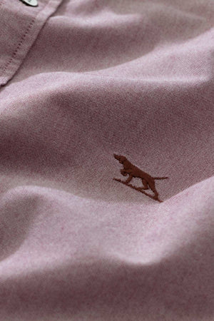 Close-up of the Rodd & Gunn Gunn Oxford Sports Fit Shirt in 100% cotton mauve, highlighted by a small embroidered brown dog in a running pose, visible stitching, and partial top button for a refined look.