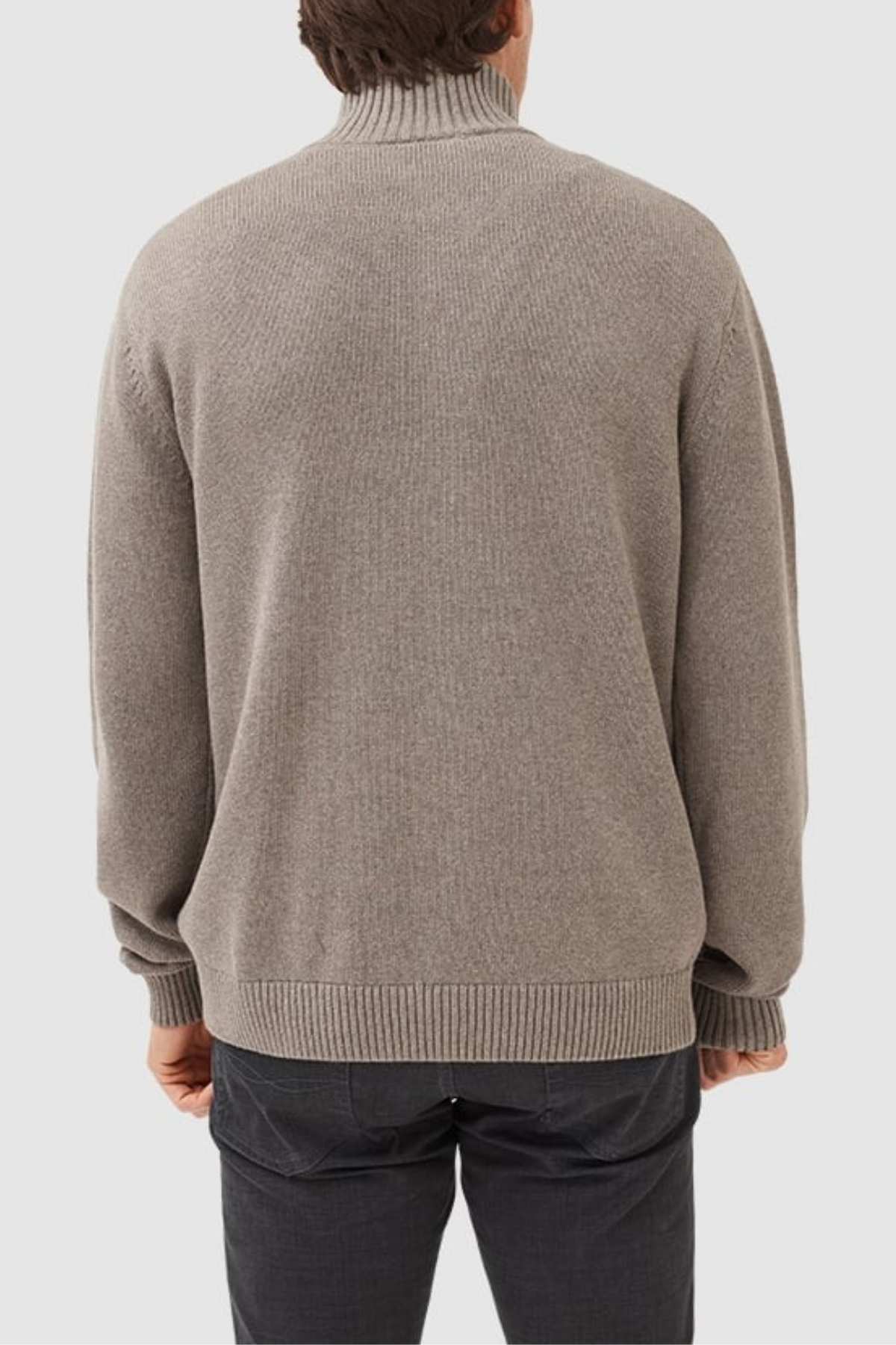 A person is seen from the back wearing a Rodd & Gunn Merrick Bay Knit light gray turtleneck sweater and dark pants, standing against a plain light background.