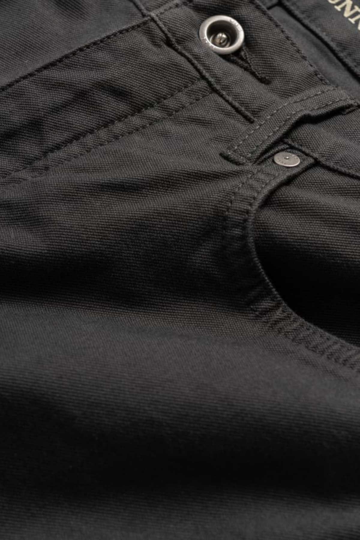 Close-up of black denim fabric from the Rodd & Gunn Motion 2 Straight Jean, featuring the front pocket, waistband with button, and YKK zip fly. Stitching details enhance the durable comfort stretch fabric, highlighting its sturdiness.