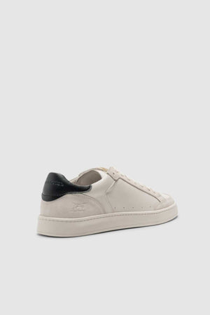 The Rodd & Gunn Sussex Street Sneaker is a white low-top with a black heel tab, subtle stitching, perforated details, a comfy leather lining, and a rubber outsole, displayed on a light gray background.