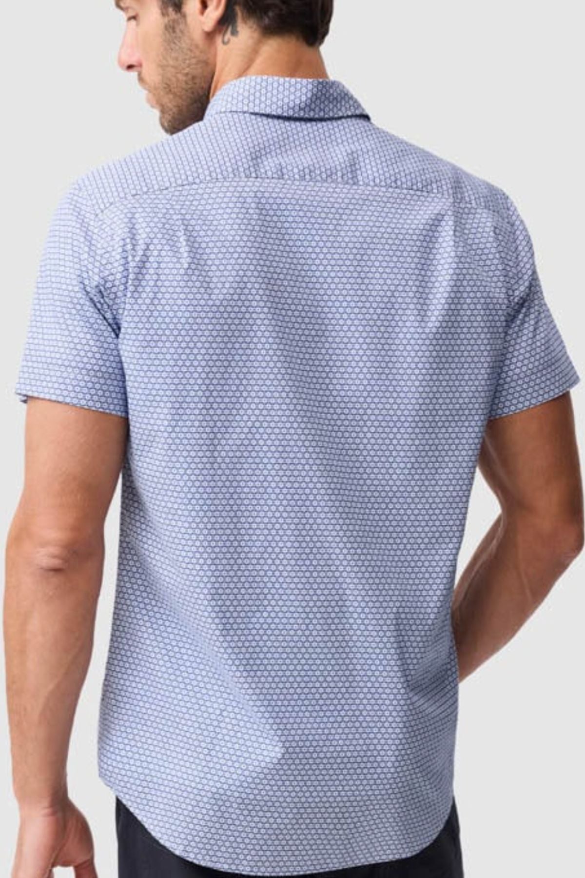 A man is seen from behind wearing the Rodd & Gunn Blumine Sports Fit Shirt, a short-sleeved, light blue patterned shirt, against a plain light background.
