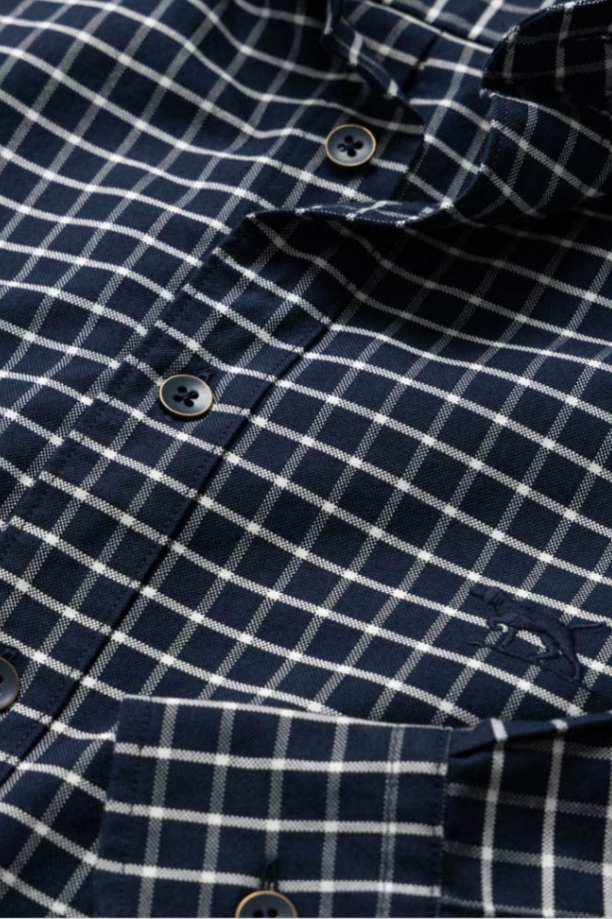 Close-up of the Rodd & Gunn Gunn Check Oxford 3 Sports Fit Shirt in navy blue and white, crafted from premium Australian cotton, featuring four buttons and a chest pocket with an embroidered logo.