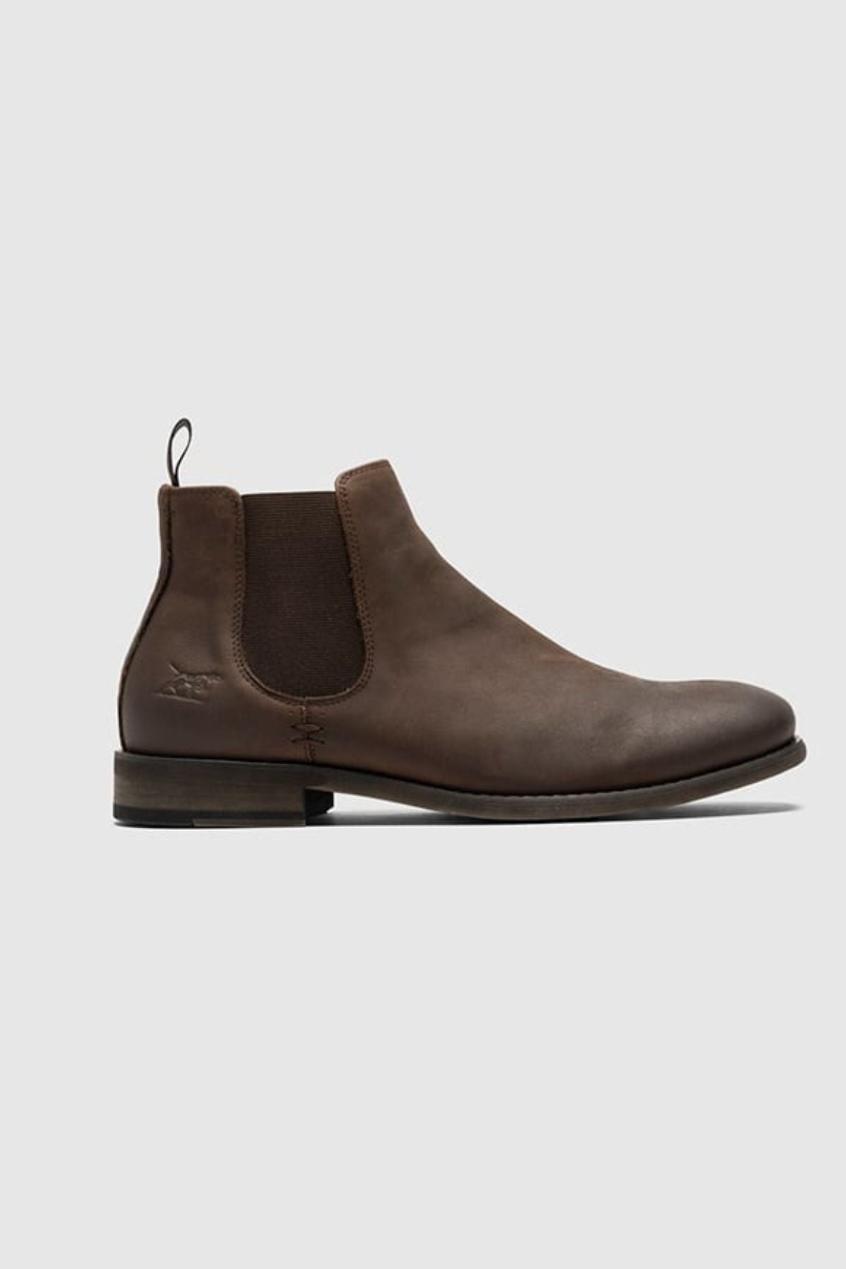 The Rodd & Gunn Ealing Chelsea Boot features brown oiled leather, elastic side panels, a heel pull tab, low stacked heel, and flexible rubber outsole. Shown on a plain light gray background.