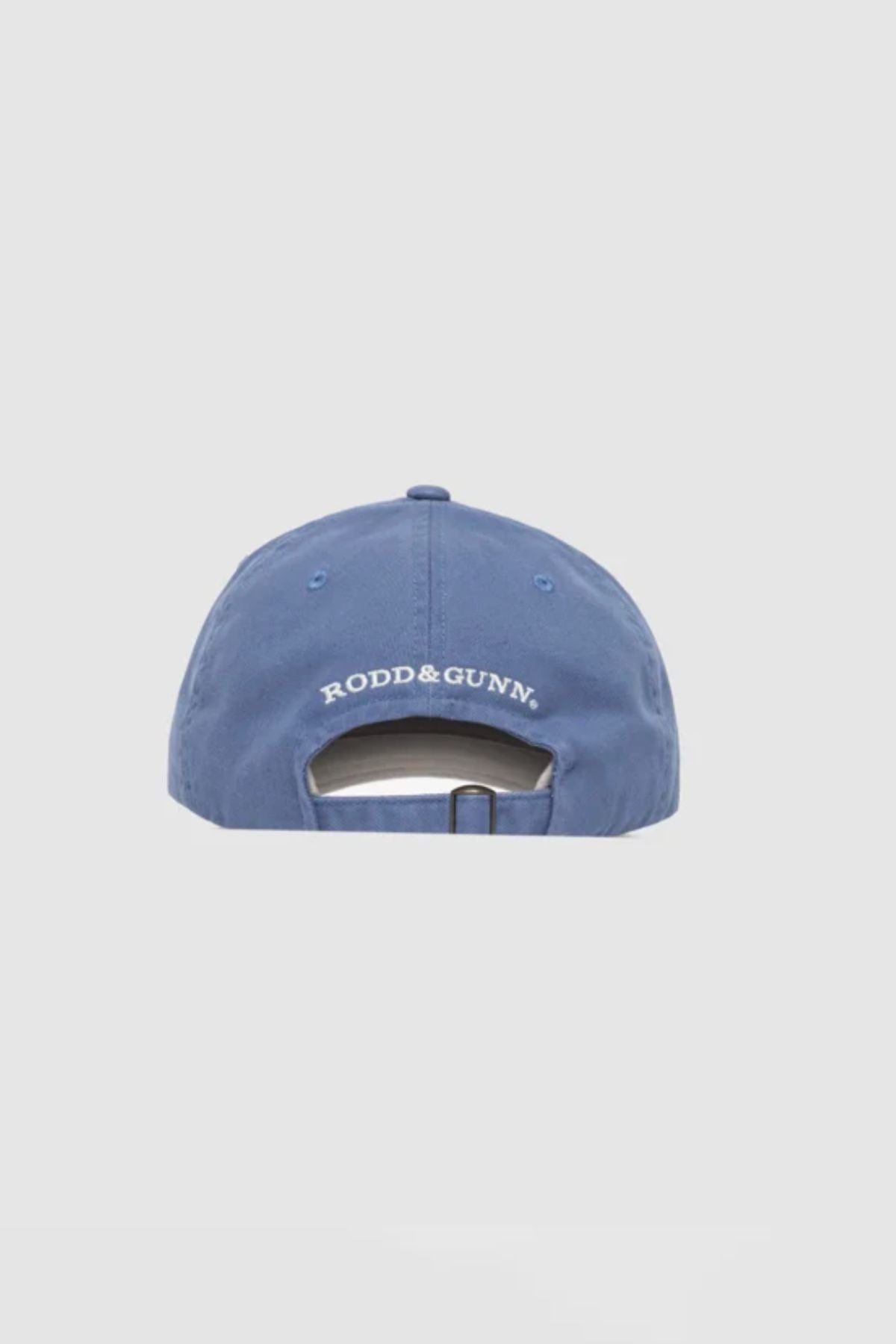 A light blue Rodd & Gunn Gunn Cap is shown from the back, with “RODD & GUNN” embroidered in white above an adjustable strap and buckle. The cotton twill cap is set against a plain, light gray background.
