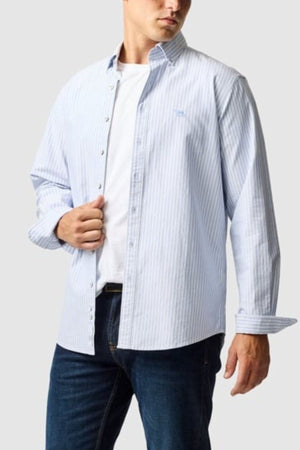 A man wears the Rodd & Gunn Gunn Oxford Stripe 4 Of Shirt over a white T-shirt and dark blue jeans, standing against a light gray background.