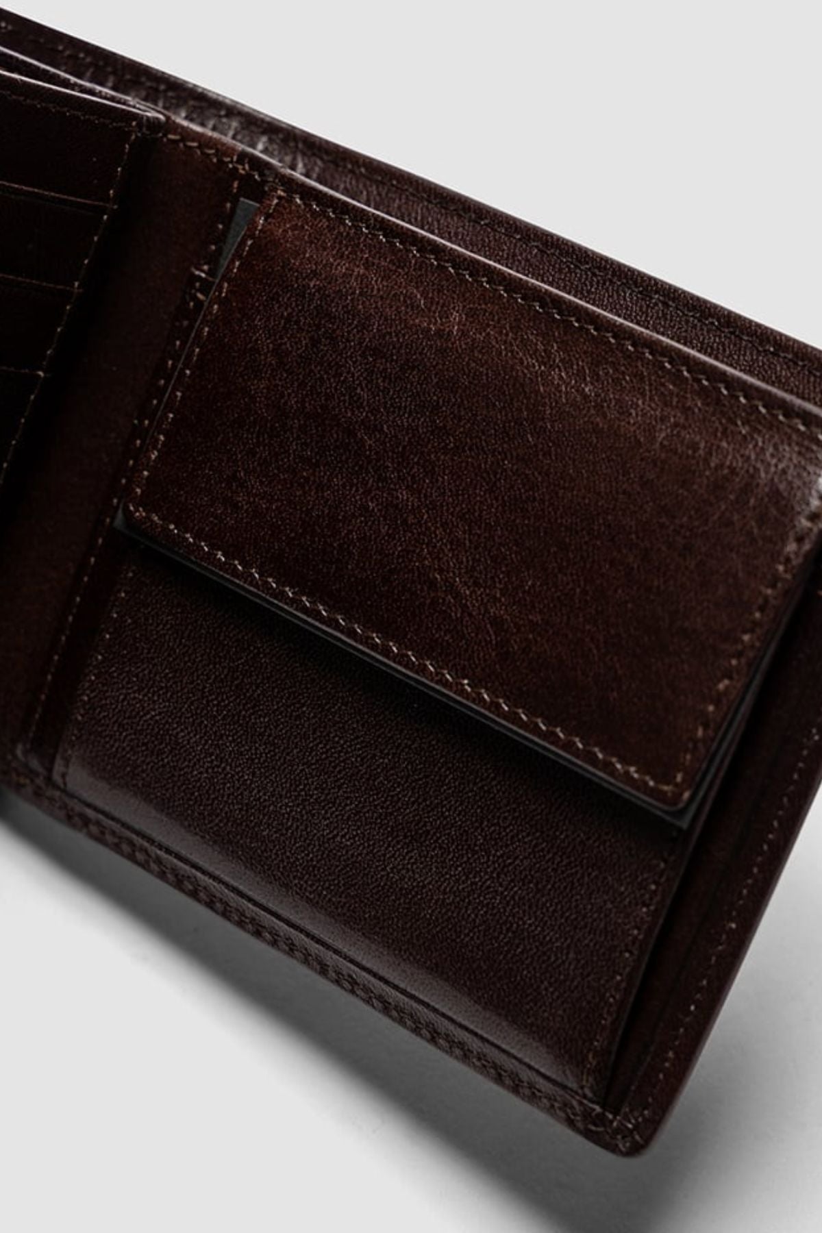 Close-up of the Rodd & Gunn Wardville Pouch Wallet in dark brown Italian leather, featuring a coin pocket with a flap and detailed edge stitching. Shown against a plain light gray background.