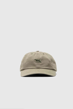 The Rodd & Gunn Gunn Cap is a must-have accessory, featuring a khaki cotton twill design with a small green embroidered dinosaur on the front, all set against a light gray background.