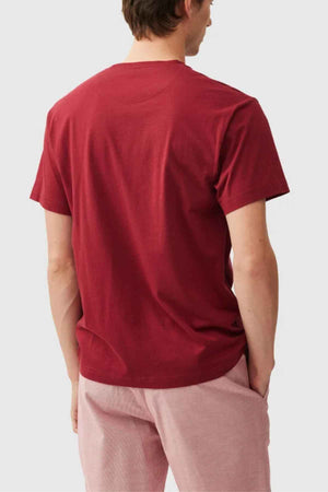 Wearing a Rodd & Gunn Logo T-Shirt crafted from sustainably farmed cotton and light pink shorts, a person stands with their back to the camera against a plain white background.