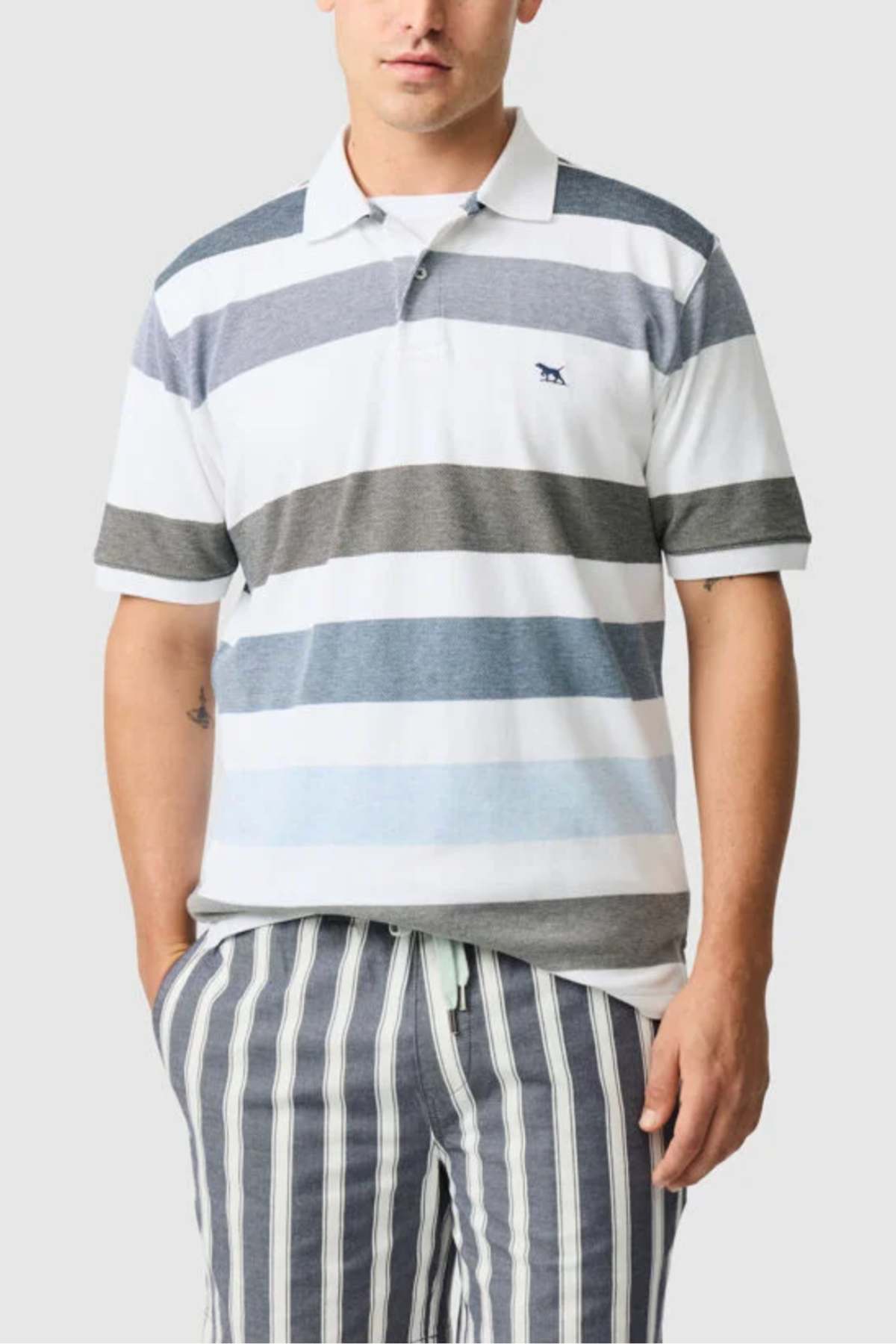 A person is wearing a Rodd & Gunn Milton Polo made from USA Cotton, featuring a striped design in white, gray, and blue with an embroidered chest logo. They are matched with blue and white striped shorts over a light gray background.