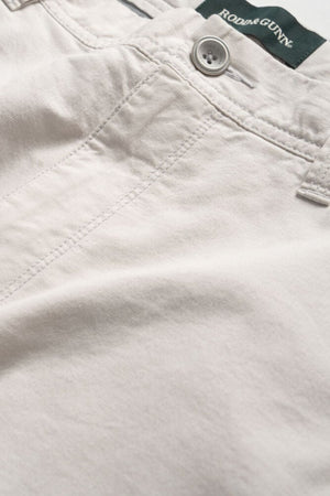 Close-up image of light beige Rodd & Gunn The Gunn Short pants with visible stitching, button, and belt loop, featuring a Rodd & Gunn label on the inner waistband. These classic fit shorts are crafted from a cotton elastane blend for added comfort and durability.