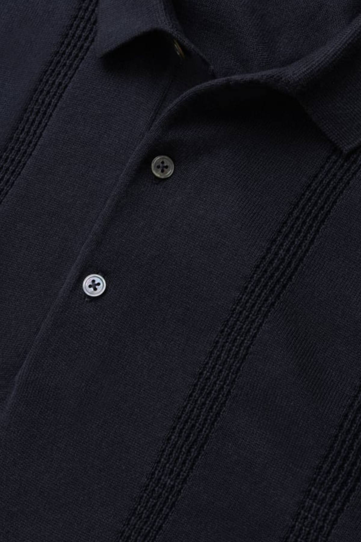 Close-up of the Rodd & Gunn Brooklands Knit, a dark navy Australian cotton polo with a collar, two buttons, and vertical textured stripes.