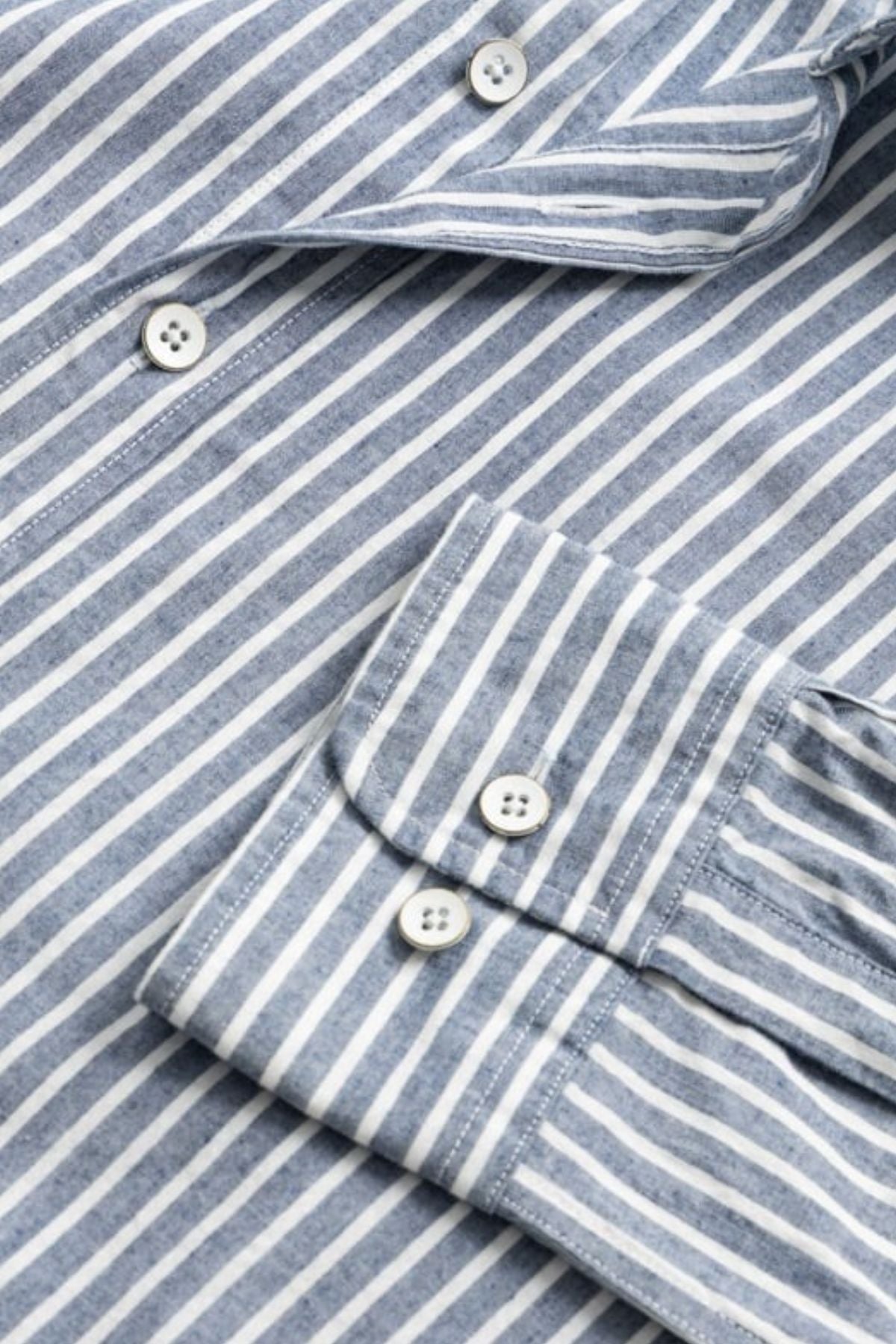 Close-up of the Rodd & Gunn Fernside Sports Fit Shirt—a blue and white vertical stripe button-down in premium European cotton—showing the two-button cuff and part of the front with visible buttons.