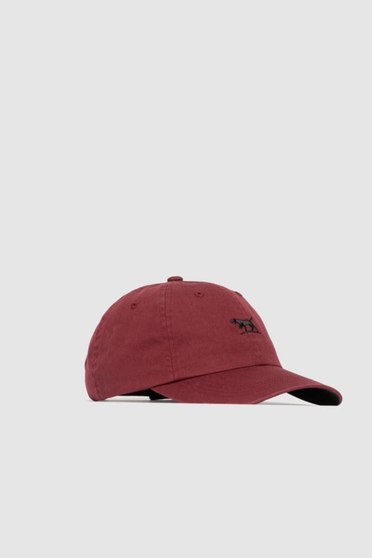 The Rodd & Gunn Gunn Cap is a maroon cotton twill cap with a curved brim and a small black embroidered pointer dog logo on the front, shown against a plain light gray background.