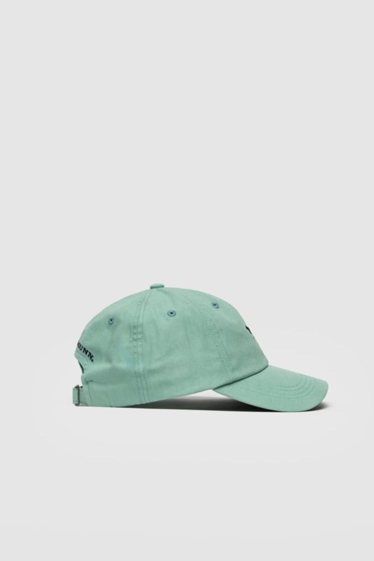 A light teal Rodd & Gunn Gunn Cap is displayed in profile on a white background. Made from cotton twill, this cap features metal eyelets and an adjustable back strap.