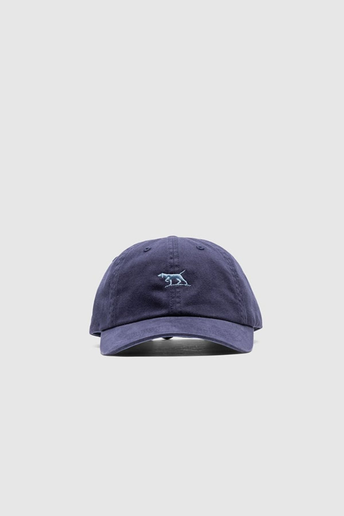 The Rodd & Gunn Gunn Cap is a navy blue cotton twill cap featuring a small light blue embroidered dog logo on the front, displayed against a plain light gray background—ideal for casual, comfortable style.