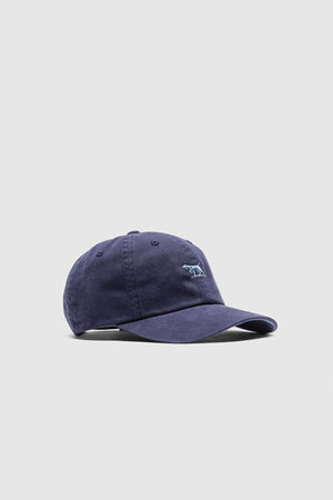 The Rodd & Gunn Gunn Cap is a navy blue cotton twill cap with a curved brim and a small embroidered dog logo on the front, shown on a plain light gray background.