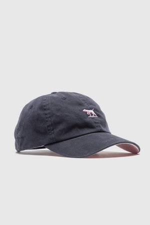 The Rodd & Gunn Gunn Cap Petite is a dark navy cotton twill cap with a curved brim, small pink embroidered dog logo on the front, light pink underside, adjustable back strap, and plain light-colored background.