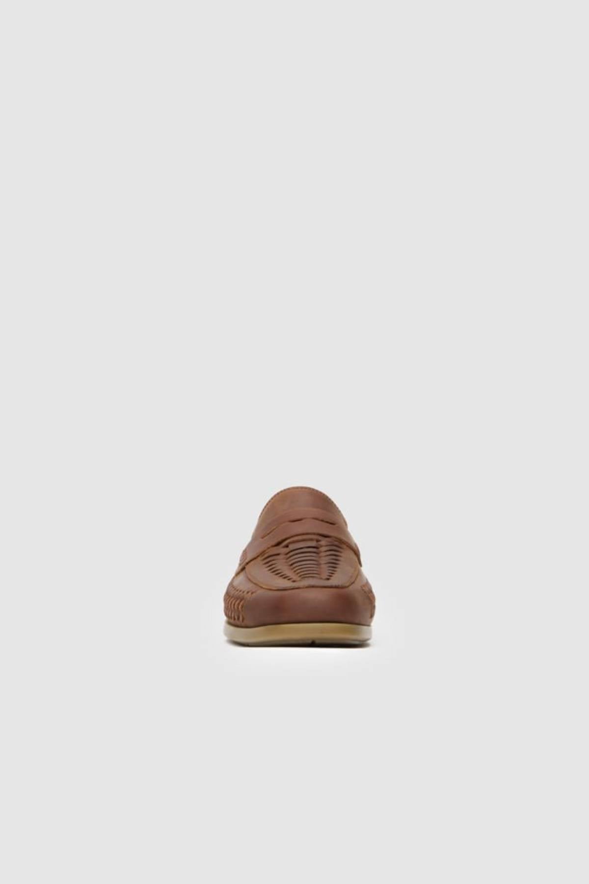 A back view of the Rodd & Gunn Gisbourne Huarache Slip On in brown leather is shown against a plain light gray background, highlighting its detailed stitching, hand-woven breathable design, and slightly textured surface.