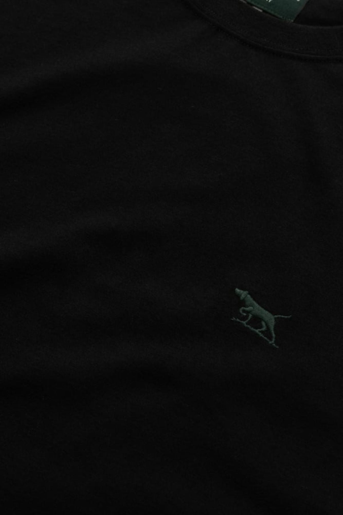 Close-up of the Rodd & Gunn The Gunn Tee 2.0, a black sports fit t-shirt made from 100% cotton, featuring a small dark green embroidered walking leopard logo on the left chest.