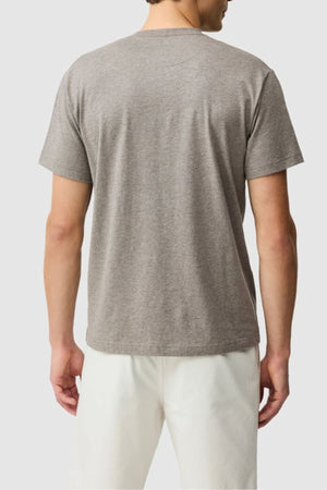 A person is seen from behind, wearing a short-sleeved gray Rodd & Gunn The Gunn Tee 2.0 and white pants, standing against a plain light background.