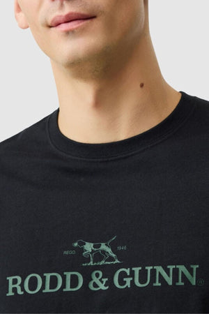 A person wears the Rodd & Gunn The Logo Tee 2.0, a black men's t-shirt featuring a green dog emblem and "RODD & GUNN" text on the front. Only the lower half of the face and upper torso are visible. Perfect for casual style.