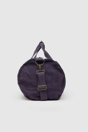 The Rodd & Gunn Ponsonby Road Duffle Bag is a round, purple cotton canvas bag with brass buckle details and a top handle, shown against a plain light gray background.