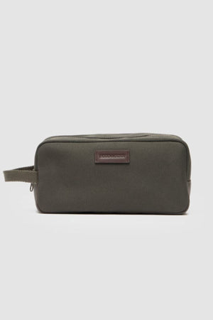 The Rodd & Gunn Ponsonby Wash Bag is a rectangular olive green cotton canvas bag with a side handle and a small leather patch on the front, shown against a plain light gray background.