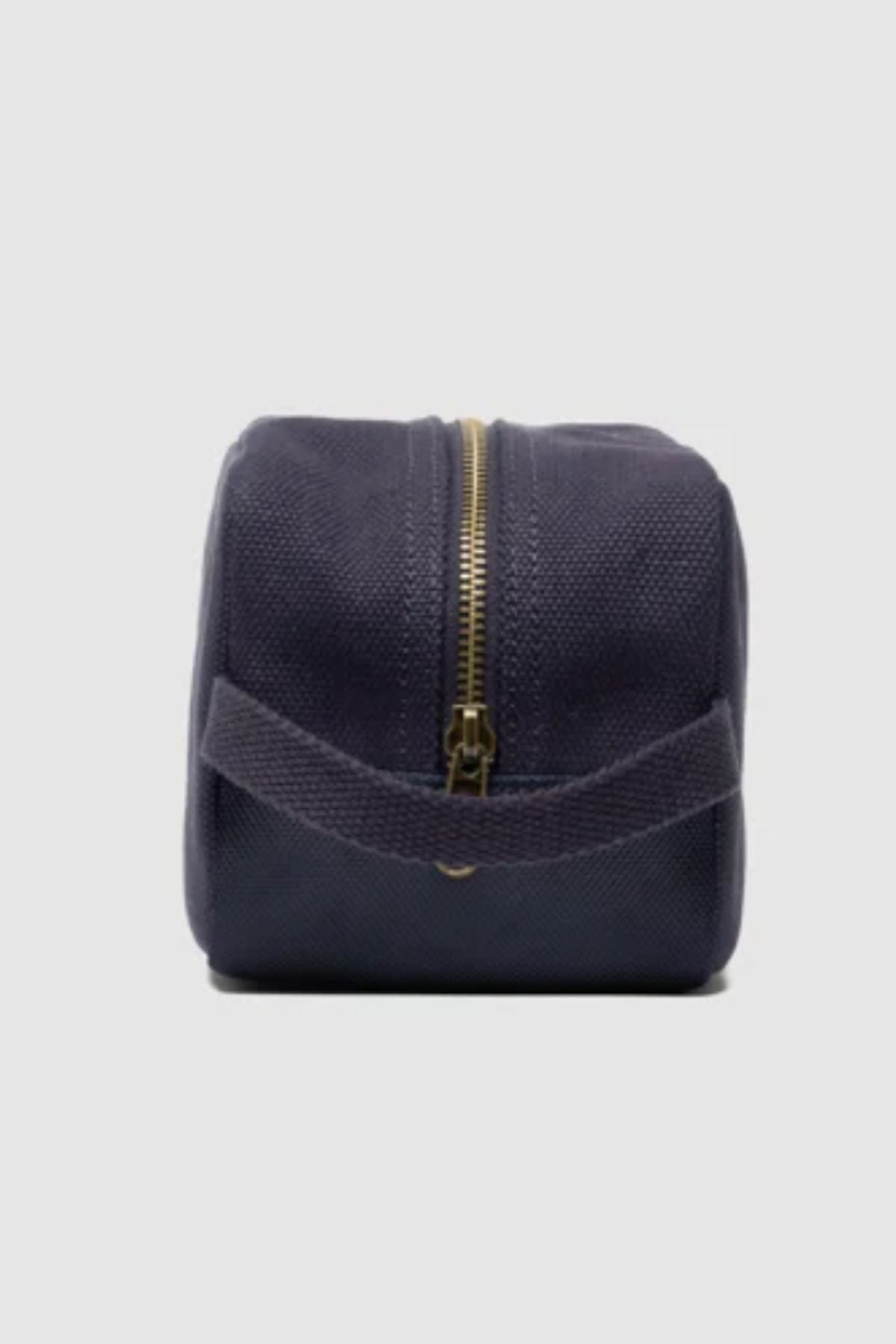 The Rodd & Gunn Ponsonby Wash Bag in navy blue cotton canvas, featuring a gold zipper and fabric handle, is displayed upright against a plain light gray background.