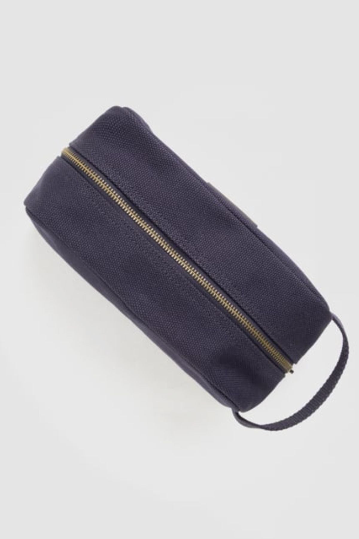 The Rodd & Gunn Ponsonby Wash Bag is a rectangular, dark navy blue cotton canvas bag featuring a brass zipper and matching handle, displayed on a light gray background.