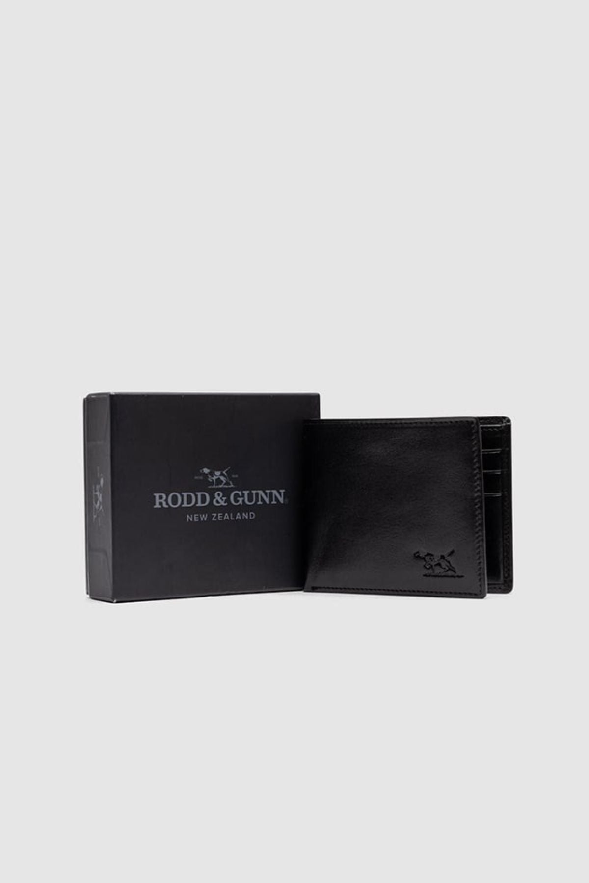 The Rodd & Gunn Wakefield Bi-Fold Wallet in black Italian leather stands open next to its matching branded box, set against a plain light gray background.