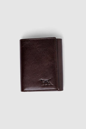 The Rodd & Gunn Westport Tri Fold Wallet, crafted from dark brown Italian leather with RFID protection and a subtle dog logo embossed in the bottom right corner, is photographed on a plain light gray background.